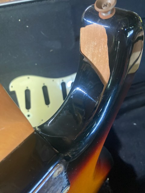 Neck pocket of a Mexican-made Fender Stratocaster with the polyester finish cracked and flaked to bare wood
